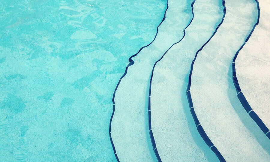 escadinha ondulada de piscina com fundo azul claro.