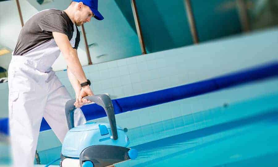 Homem limpando a água da piscina.