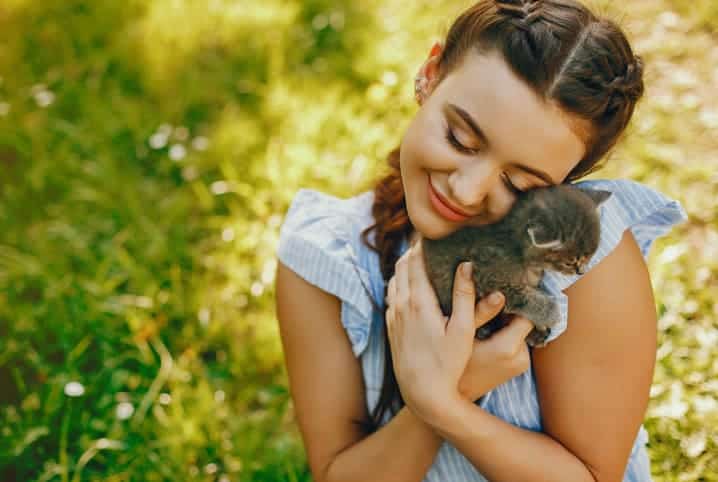 menina abraçando gato filhote