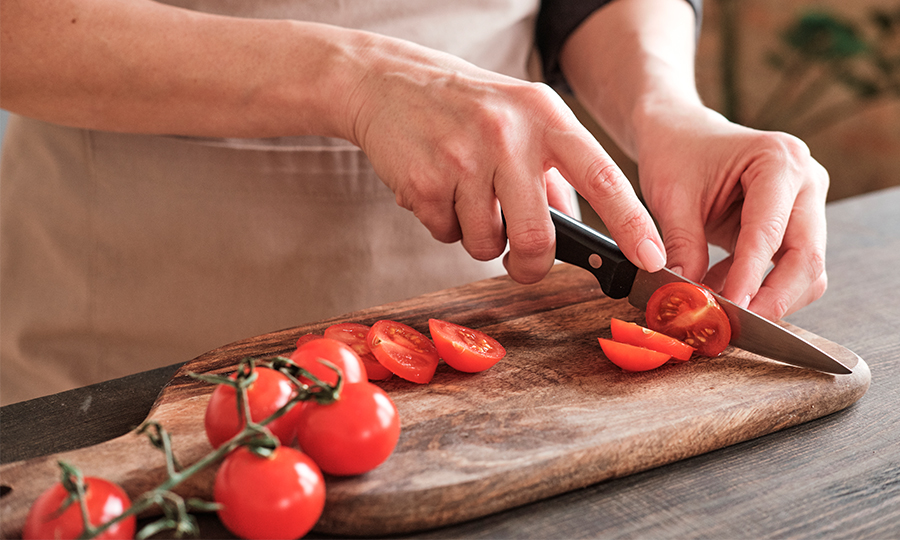 Pessoa fatiando tomates.