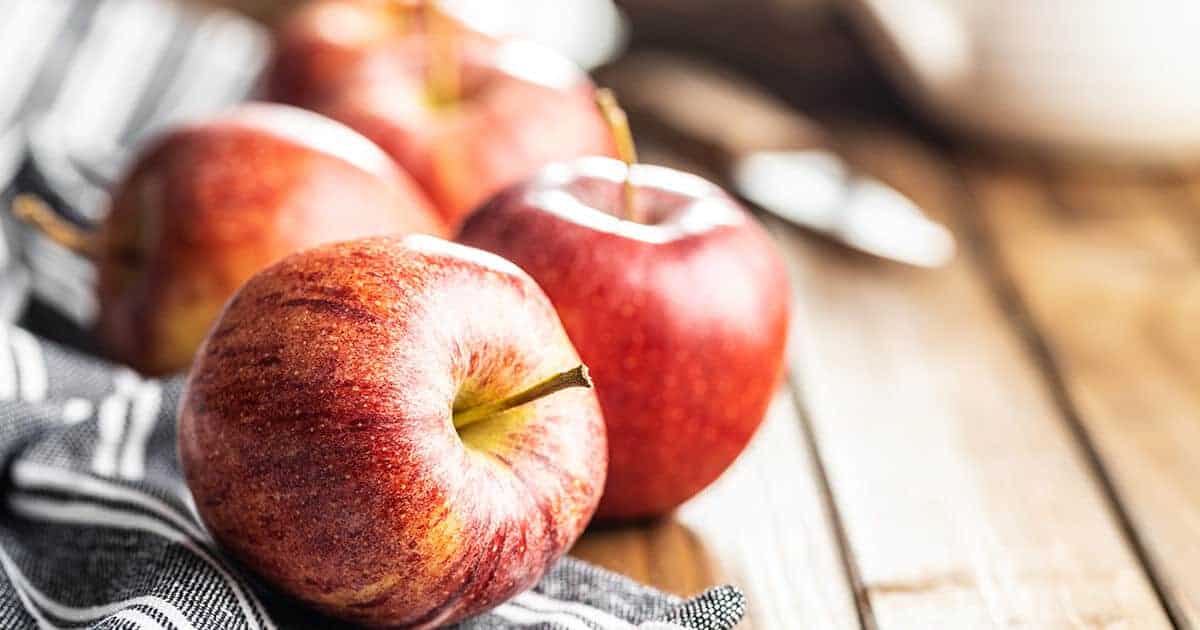 Maçãs vermelhas em cima de uma mesa de madeira.