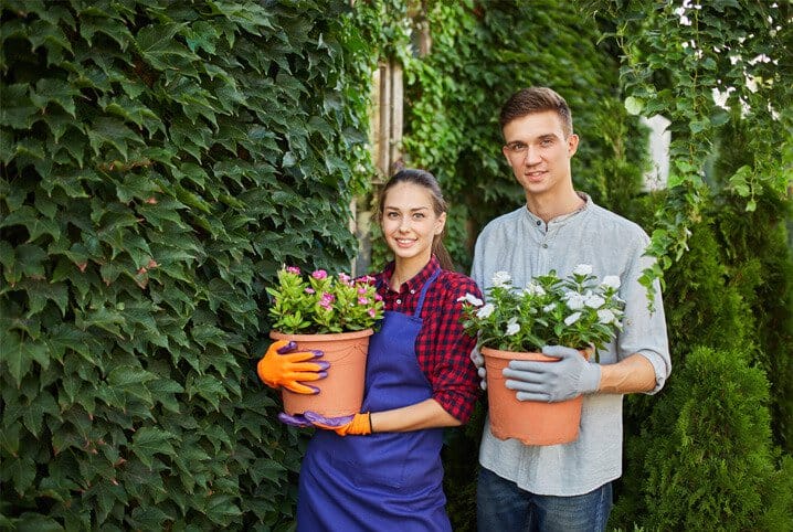 Homem e mulher segurando vasos de flores.