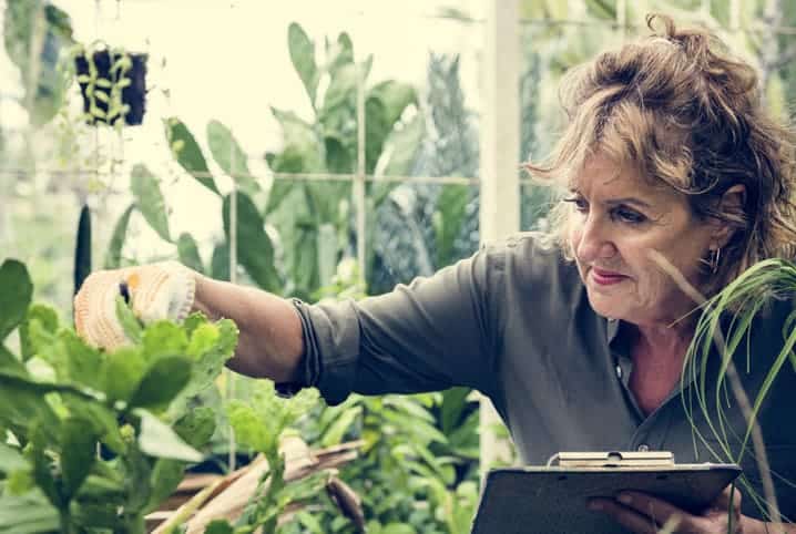 Mulher olhando as plantas do jardim.