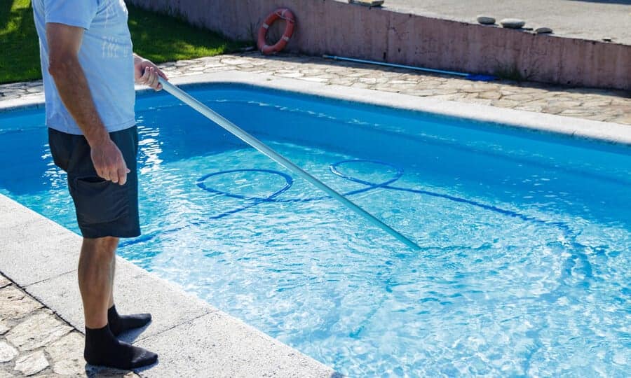 Homem limpando a piscina.